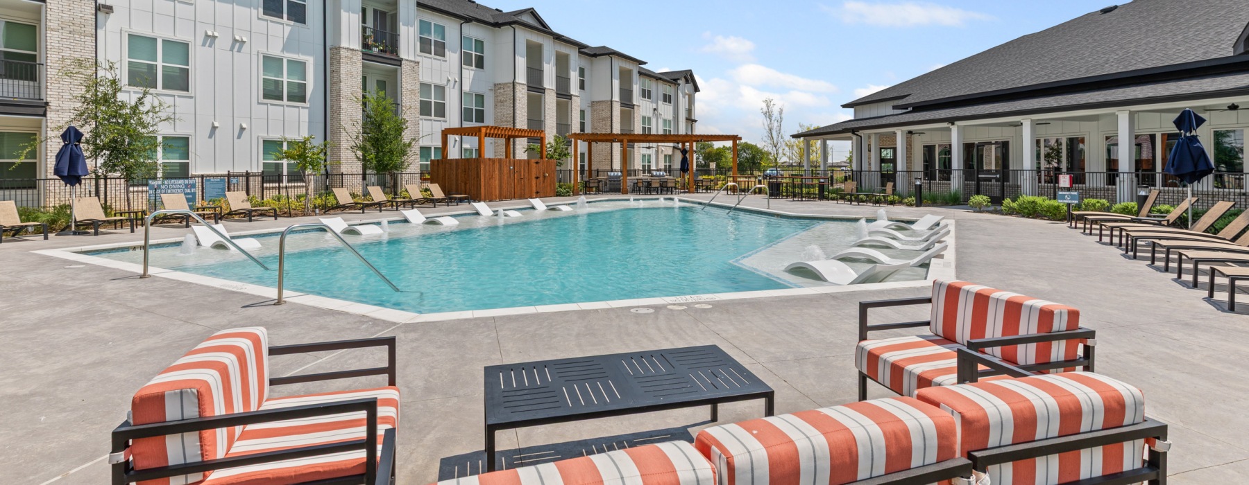 Pool with sun deck and lounge seating at Peak at 1385 luxury apartments in Aubrey, TX.