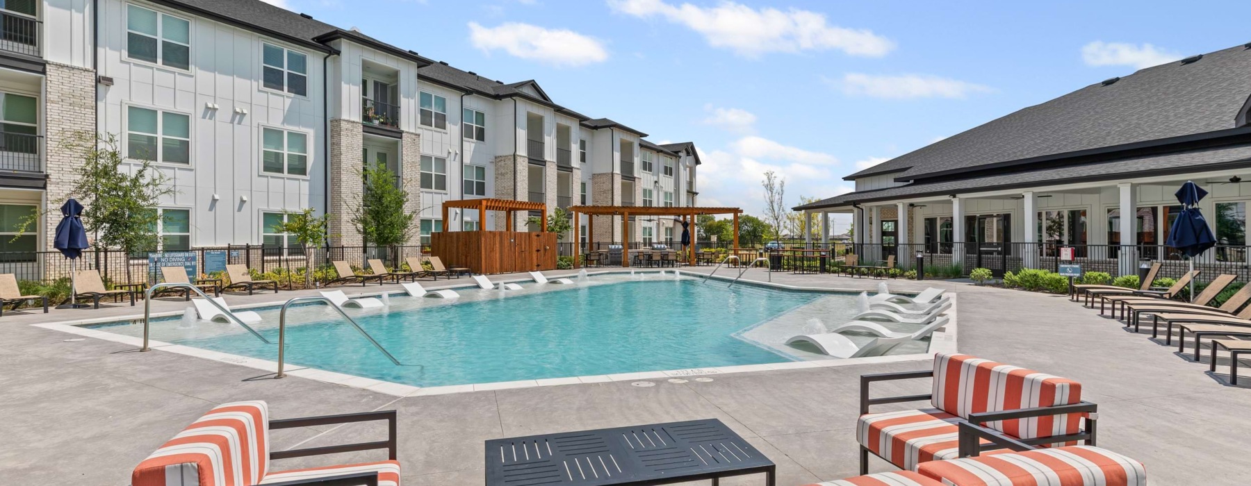 Pool with sun deck and lounge seating at Peak at 1385 luxury apartments in Aubrey, TX.
